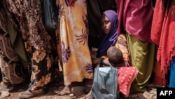 Seorang wanita menggendong anaknya saat menunggu pembagian makanan bergizi tinggi dan konsultasi medis di kamp Tawkal 2 Dinsoor di Baidoa, Somalia, 14 Februari 2022. (Foto: AFP