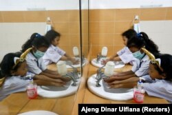 Siswa SD yang memakai masker sedang mencuci tangan usai sekolah, di Jakarta, 9 Maret 2020. Cuci tangan dapat mencegah terjadinya penularan hepatitis. (Foto: REUTERS/Ajeng Dinar Ulfiana)