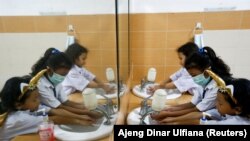 Siswa SD yang memakai masker sedang mencuci tangan usai sekolah, di Jakarta, 9 Maret 2020. (Foto: REUTERS/Ajeng Dinar Ulfiana)