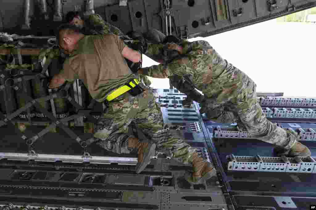 Airmen push over 8,000 pounds of 155 mm shells on to a C-17 cargo aircraft for transport, ultimately bound for Ukraine, April 29, 2022, at Dover Air Force Base, Del. 