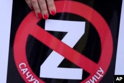 Žena drži transparent sa precrtaim latiničnim slovom "Z", koje je postalo simbol ruske vojske u Ukrajini i natpisom "Sačuvajmo ćirilicu", tokom protesta protiv rata u Ukrajini, u Beogradu, Srbija, 28. maja 2022.