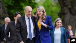 参加在德国小镇旺格尔斯召开的2022年七大工业国集团外长会议的各国外长。法国外长让-伊夫∙勒德里昂（Jean-Yves Le Drian）（前左）和加拿大外长茉兰妮娅·茱莉（Melanie Joly）边走边谈。