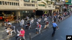 FILE - Workers wear face masks and practice social distancing while they wait to be tested for the coronavirus at Khaosan road Thursday, Jan. 6, 2022, in Bangkok.
