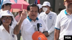 ប្រធាន​គណបក្ស​កម្ពុជា​និយម​លោក​យ៉ែម បុញ្ញឫទ្ធិ​ ឈរ​ក្បែរ​បេក្ខជន​ជា​ស្ត្រី​សម្រាប់​តំណែង​ចៅ​សង្កាត់​បឹង​ទំពន់ទី​២ អំឡុង​ពេល​ធ្វើ​យុទ្ធនា​ការ​ឃោសនា​បោះឆ្នោត​ ថ្ងៃអាទិត្យ​ ទី​២៩ ខែ​ឧសភា​​ ឆ្នាំ​ ២០២២​។ (ហ៊ុល រស្មី/វីអូអេ)​​​​