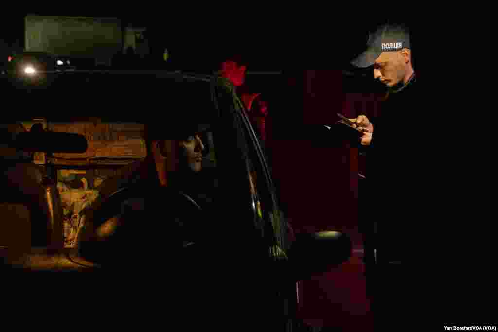 A police officer checks the documents of a man who had just left Mariupol in a civilian convoy, at a refugee center in Zaporizhzhia, May 4, 2022. (Yan Boechat/VOA) 