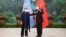 In this photo released by Xinhua News Agency, Chinese Foreign Minister Wang Yi, right, poses for photo with the United Nations High Commissioner for Human Rights Michelle Bachelet in Guangzhou, in southern China's Guangdong province, May 23, 2022.