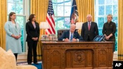 Predsednik SAD Džo Bajden potpisuje zakon o pomoći Ukrajini okružen članovima Kongresa, u Ovalnom kabinetu, u Beloj kući, 9. maja 2022.