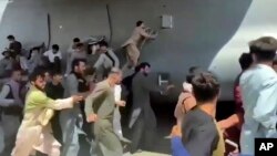 Arhiva - Desetine ljudi trče pored transportnog aviona C-17 američkog vazduhoplovstva dok letelica rula pistom međunarodnog aerodroma, u Kabulu, Avganistan, 16. avgusta 2021.