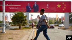 រូប​ឯកសារ៖ ស្ត្រី​ម្នាក់​ឆ្លង​ផ្លូវ​នៅ​ក្បែរ​បដា​មួយ​ដែល​បង្ហាញ​ពី​ទស្សនកិច្ច​ផ្លូវ​រដ្ឋ​របស់​ប្រធានាធិបតី​ចិន​លោក Xi Jinping នៅ​ទី​ក្រុង​ព័រម៉ូរេសប៊ី ប្រទេស​ប៉ាពូអាស៊ីនូវែលហ្គីណេ កាល​ពី​ថ្ងៃ​ទី​១៥ ខែ​វិច្ឆិកា ឆ្នាំ ២០១៨។ 