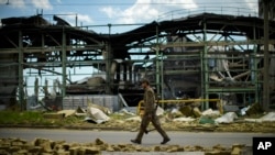 FILE - A Ukrainian serviceman walks past a gypsum manufacturing plant destroyed in a Russian bombing in Bakhmut in eastern Ukraine, May 28, 2022.