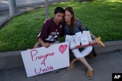 Diego Esquivel, kiri, dan Linda Klaasson saling menghibur saat menghormati para korban tewas dalam penembakan di Sekolah Dasar Robb di Uvalde, Texas, Rabu, 25 Mei 2022. (Foto: AP)
