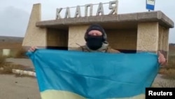 一名乌克兰士兵在南部赫尔松地区的一个村庄里展示乌克兰国旗。（2022年11月11日）