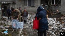 Stanovnici pored uništene kuće nakon ruskog raketnog napada na Časiv Jar, 27. novembar 2022.