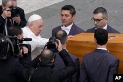 FILE - Pope Francis touches the coffin of late Pope Emeritus Benedict XVI before it is carried away after a funeral mass in St. Peter's Square at the Vatican on Jan. 5, 2023.