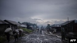 Après la pluie, des commerçants quittent le marché avec leurs bagages à la dot à Kitshanga, à 90 kilomètres de la ville de Goma dans l'est de la République démocratique du Congo le 10 décembre 2022.