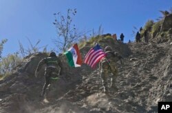 Seorang tentara India dan AS, masing-masing membawa bendera negaranya, berlari ke atas bukit selama pertemuan bersama Indo-AS. latihan militer di negara bagian Uttarakhand, India, 30 November 2022. (Foto: AP)
