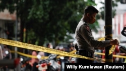 Seorang petugas polisi memasang garis penjagaan di Bandung, Jawa Barat, sebagai ilustrasi. Seorang perempuan yang dituduh sebagai penculik anak, dianiaya dan dibakar di Sorong, Papua. (Foto: REUTERS/Willy Kurniawan)