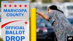 FILE - A voter drops off her ballot at a drop box, Nov. 7, 2022, in Mesa, Ariz.