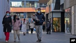 FILE - People walk through a reopened open air shopping mall in Beijing, Dec. 4, 2022. 