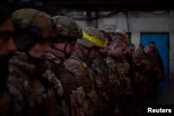 Ukrajinski vojnici odaju počast palim saborcima tokom posete predsednika Ukrajine Volodimira Zelenskog njihovim pozicijama na liniji fronta u Bahmutu, tokom ruskog napada na Ukrajinu, u oblast Donjecka, 20. decembra 2022, na fotografiji koju je objavila Kancelarija predsednika Ukrajine (Foto: Rojters)