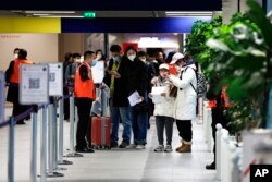 Penumpang yang tiba dari China menunggu di depan area pengujian COVID-19 yang ditetapkan di Bandara Roissy Charles de Gaulle, utara Paris, Minggu, 1 Januari 2023. (Foto: AP)