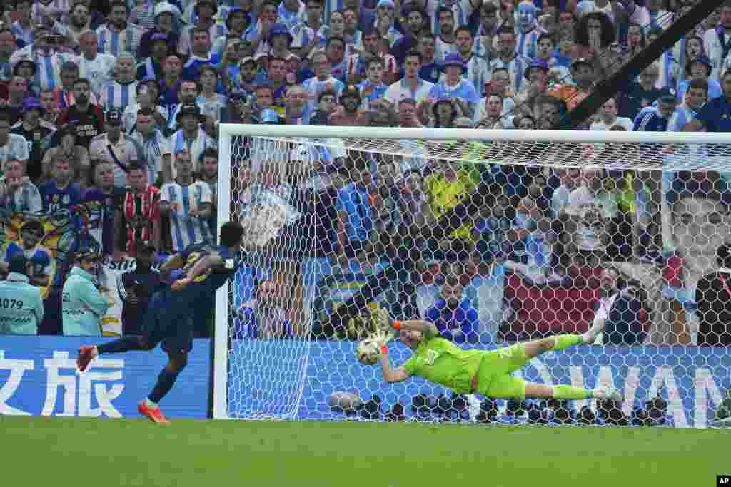 Argentina's goalkeeper Emiliano Martinez blocks a shot from France's Kingsley Coman in a penalty shootout during the World Cup final soccer match between Argentina and France at the Lusail Stadium in Lusail, Qatar, Dec. 18, 2022.