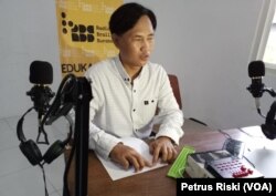 Tutus Setiawan membacakan berita dari teks braille yang dibuat sebelumnya. (Foto: VOA/Petrus Riski)