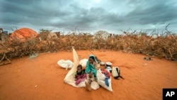 Žena i dete iz Somalije čekaju da im se pruži mesto za smeštaj u kampu za raseljene ljude usred suše na periferiji Doloua. Somalija, 20. septembar, 2022. (Foto: AP/Jerome Delay)