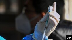 In this photo released by Xinhua News Agency, a medical worker prepares to administer a second booster dose of COVID-19 vaccine at a temporary vaccination site in Beijing, Dec. 17, 2022. 
