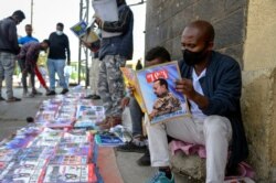 Ethiopians read newspapers and magazines reporting on the current military confrontation in the country, one of which shows a photograph of Prime Minister Abiy Ahmed, on a street in the capital Addis Ababa, Ethiopia, Nov. 7, 2020.