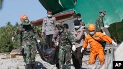 Petugas penyelamat membawa tubuh korban gempa yang ditemukan di antara puing-puing sebuah masjid yang robih di Lombok Utara, Indonesia, 7 Agustus 2018. 