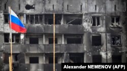 俄罗斯国旗竖立在马里乌波尔一座被摧毁的建筑外。(2022年4月12日)