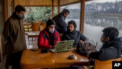 FILE- Fahad Shah, center sitting, editor-in-chief of The Kashmir Walla, and other Kashmiri Journalists prepare for a meeting to discuss the shutting of Kashmir Press Club building, the region's only independent press club, in Srinagar, Indian-controlled Kashmir, Jan. 20, 2022.