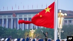 Seorang anggota pengawal kehormatan China membentangkan bendera nasional China dalam upacara pengibaran bendera menandai berdirinya Republik Rakyat China di Lapangan Tiananmen, Beijing, 1 Oktober 2022.