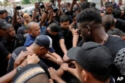 Para pemain dan ofisial klub Arema FC melakukan salat di luar Stadion Kanjuruhan di mana banyak suporter kehilangan nyawa akibat terinjak-injak Sabtu malam di Malang, Senin, 3 Oktober 2022. (Foto: AP)