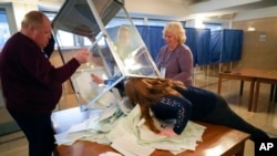 Anggota komite referendum mengosongkan kotak suara untuk memulai perhitungan soal referendum di sebuah tempat pemungutan suara di Luhansk, Ukraina, pada 27 September 2022. (Foto: AP)