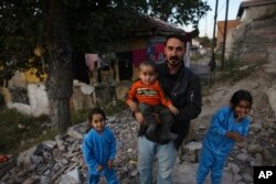Migran Suriah Mohammad Dima bersama anak-anaknya di depan penampungan mereka di distrik Ulus, bagian lama ibu kota Turki, Ankara, Turki, Minggu, 23 Oktober 2022. (AP/Burhan Ozbilici)