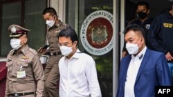 This picture taken on April 17, 2022 shows Prinn Panitchpakdi (C), a former deputy of Thailand's Democrat Party, as he leaves a police station in Bangkok on his way to court to ask for bail. (Photo by Tananchai KEAWSOWATTANA / THAI NEWS PIX / AFP)