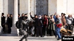 Anggota pasukan keamanan Israel menodongkan senjata ke arah jemaah Palestina di kompleks masjid Al-Aqsa pada bentrokan hari Jumat (15/4). 