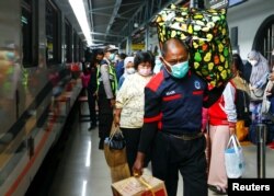 Penumpang membawa barang bawaan mereka saat mereka berjalan di stasiun kereta api untuk mudik, menjelang perayaan Idul Fitri, di tengah wabah COVID-19 di Jakarta, 5 Mei 2021. (REUTERS/Ajeng Dinar Ulfiana)