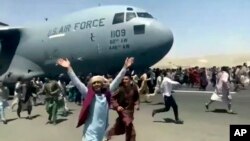 Ratusan warga Afghanistan berebut untuk naik ke pesawat C-17 Angkatan Udara AS di bandara internasional Kabul, Senin (16/8). 