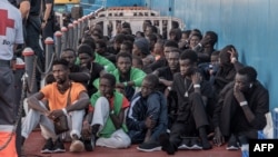 资料照片: 2023年10月12日移民在西班牙下船后坐在地上