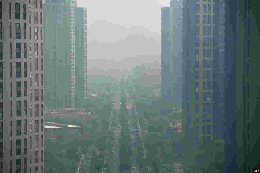 2018年8月6日,江苏省南京市空气污染的一天,高楼、绿树、公路、汽车都在雾霾中。南京《交汇点》8月14日报道说,臭氧污染“大有取代PM2.5之势,成为影响空气质量的最大污染物之一,近五年来,臭氧一直笼罩在南京城上空,最近三年,臭氧超标均超过50天。 ”