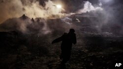 Migrants run as tear gas is thrown by U.S. Border Protection officers to the Mexican side of the border fence after they climbed the fence to get to San Diego, Calif., from Tijuana, Mexico, Jan. 1, 2019. 