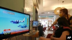 FILE - A customer and a staff member watch a news report on the recent tensions between China and Taiwan, at a beauty salon in Taipei, Taiwan, Aug. 4, 2022.