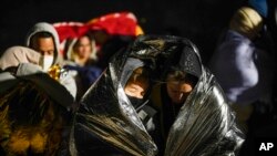 FILE - Two women from Cuba try to keep warm after crossing the border from Mexico and surrendering to authorities to apply for asylum, Nov. 3, 2022, near Yuma, Arizona.