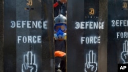 资料照片: 2021年3月11日,一名反政变抗议者从缅甸仰光设立的临时路障空隙中窥视。(美联社照片)