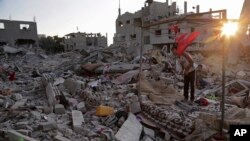 Ahmad and Mahmoud al Masri sit during the sunset on the rubble of their family house destroyed by Israeli strikes in the town of Beit Hanoun, in the northern Gaza Strip, Aug. 12, 2014. 