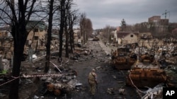 Seorang prajurit Ukraina berjalan di tengah tank Rusia yang hancur di Bucha, di pinggiran Kyiv, Ukraina, 6 April 2022. (Foto: AP)