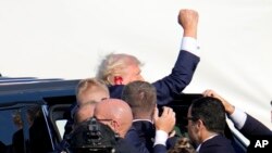 Kandidat presiden AS dari Partai Republik, Donald Trump, mengepalkan tangannya saat ia dibawa masuk ke dalam mobil sesaat setelah penembakan terjadi kepadanya dalam kampanye di Butler, Pennsylvania, pada 13 Juli 2024. (Foto: AP/Gene J. Puskar)